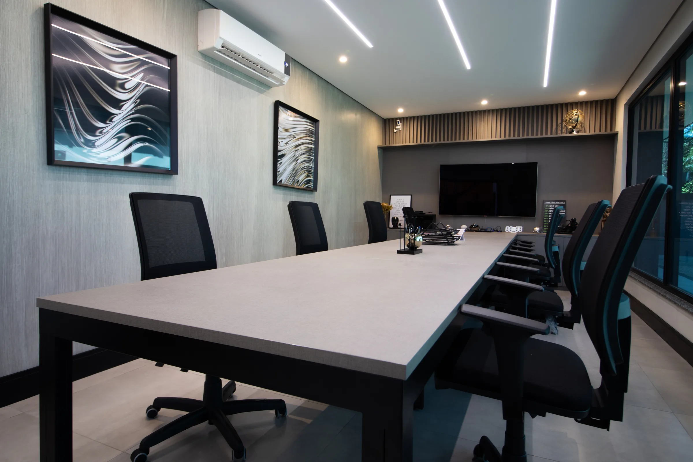 Sala de reunião da Apice, com mesa grande, televisão e luz natural.